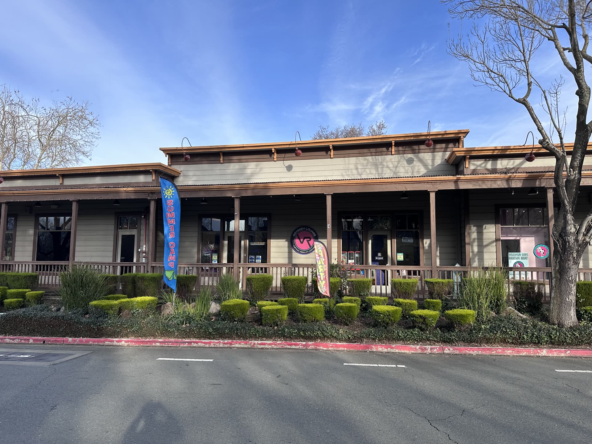 The Odyssey VR Lounge storefront, with the round VR sign beside the entrance and party and summer camp flags out front